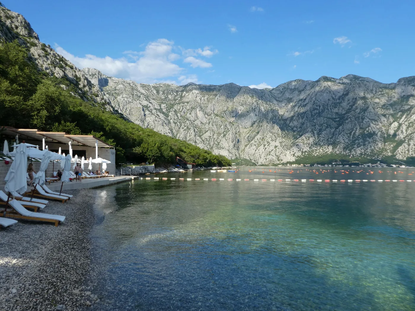 Clear turquoise water and green hillsides at Bajova Kula Beach on the coastal road between Kotor and Perast